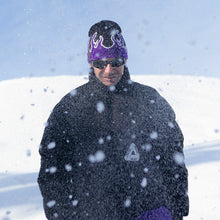 Load image into Gallery viewer, Stay warm and stylish with the NG Graphic Beanie. Featuring bold graphics and our signature &#39;No Bullshit, Just Riding&#39; label, it&#39;s perfect for snowboarding, skiing, and everyday winter wear. 100% acrylic for comfort and durability. Shop now! Purple fire on Snow. Model. Absolut Park. Design.