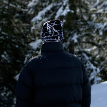 Load image into Gallery viewer, Stay warm and stylish with the NG Graphic Beanie. Featuring bold graphics and our signature &#39;No Bullshit, Just Riding&#39; label, it&#39;s perfect for snowboarding, skiing, and everyday winter wear. 100% acrylic for comfort and durability. Shop now! Black Flash on Snow. Model. Absolut Park. Chillhouse.