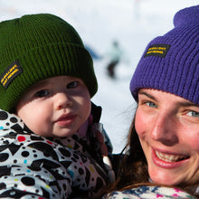 Load image into Gallery viewer, Shop our Kids Classic Beanie—small fit, 100% acrylic, perfect for kids who love snowboarding, skiing, and staying warm. Featuring the &quot;No bullshit, just riding&quot; label, this beanie combines style and warmth for all winter adventures. Ideal winter gear for young shredders! Kids Model. Green Color. Purple Beanie. 