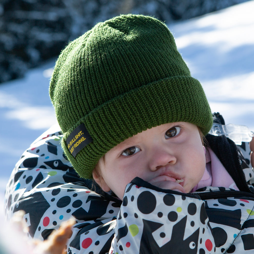 Shop our Kids Classic Beanie—small fit, 100% acrylic, perfect for kids who love snowboarding, skiing, and staying warm. Featuring the "No bullshit, just riding" label, this beanie combines style and warmth for all winter adventures. Ideal winter gear for young shredders! Kids Model. Green Color.