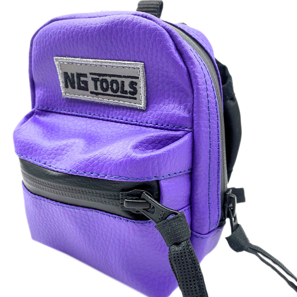 NG Snowboard Binding Bag in Purple leather in Detail, securely attached to a snowboard binding. High-back snowboard backpack for carrying tools, wax, or essentials while riding.